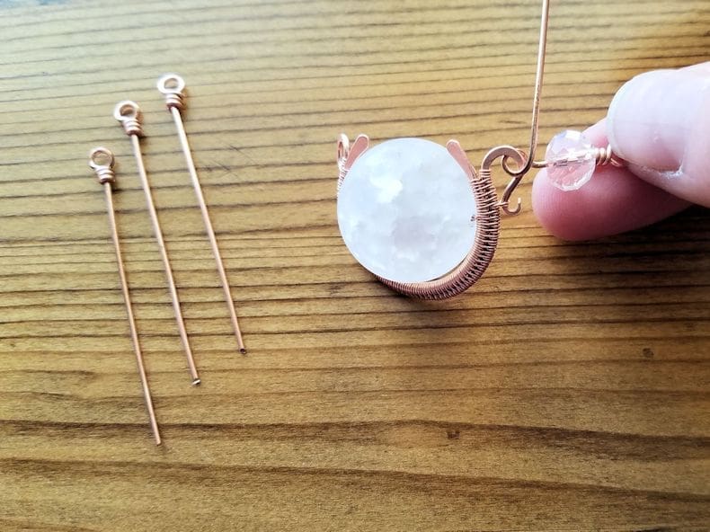 Pendant Step 3 - Thread an accent bead onto one looped head pin and begin a second loop beneath the bead. Attach the loop to one large loop on a beaded component before completing the wrapped loop, as shown.