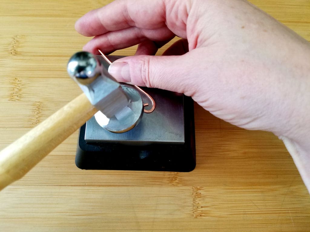 Here I'm beginning to hammer the curl on the end of my wire, starting from the front edge of the curl.