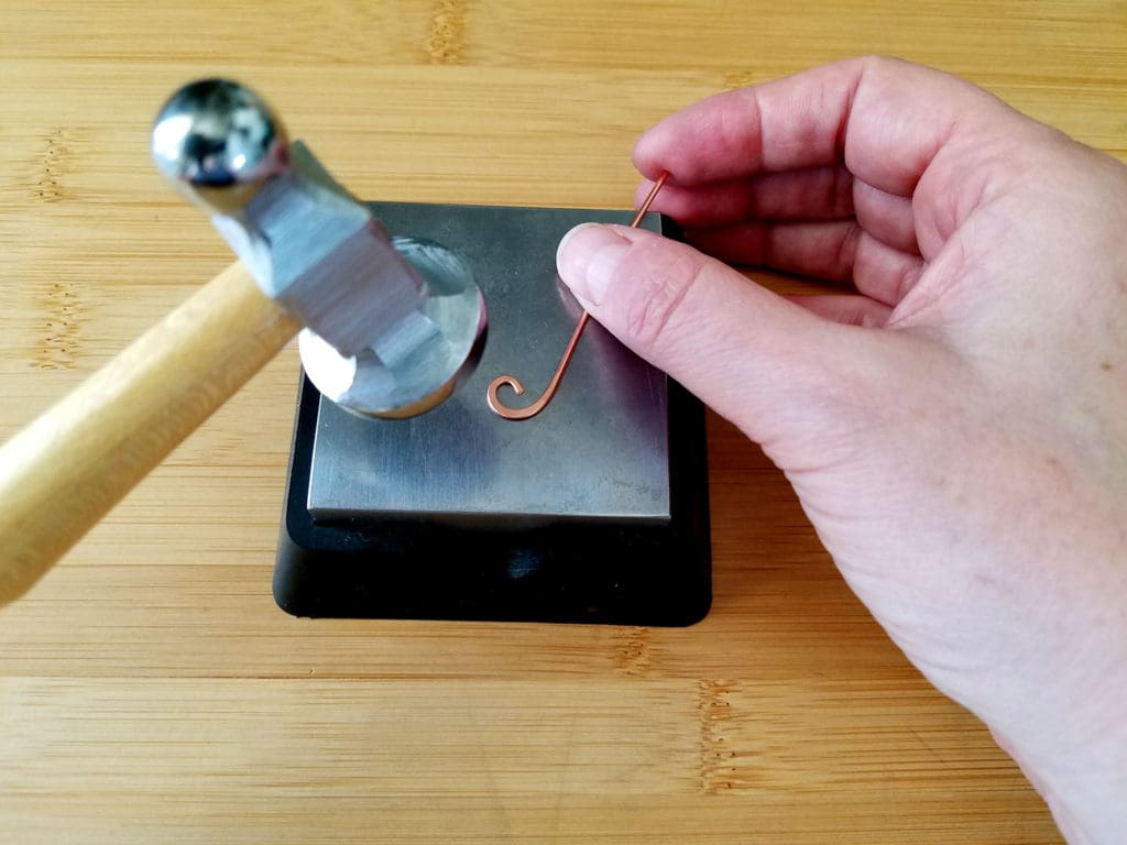 As I continue hammering the curl, I adjust the position of the wire with my free hand and keep my hammer in the same position, as shown.
