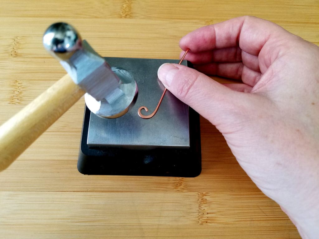 As I continue hammering the curl, I adjust the position of the wire with my free hand and keep my hammer in the same position, as shown. 