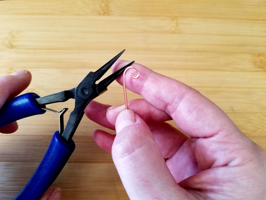 Here I made a simple curl on the end of a piece of scrap wire with my chain nose pliers. We're now going to hammer this curl to create more dimension. 