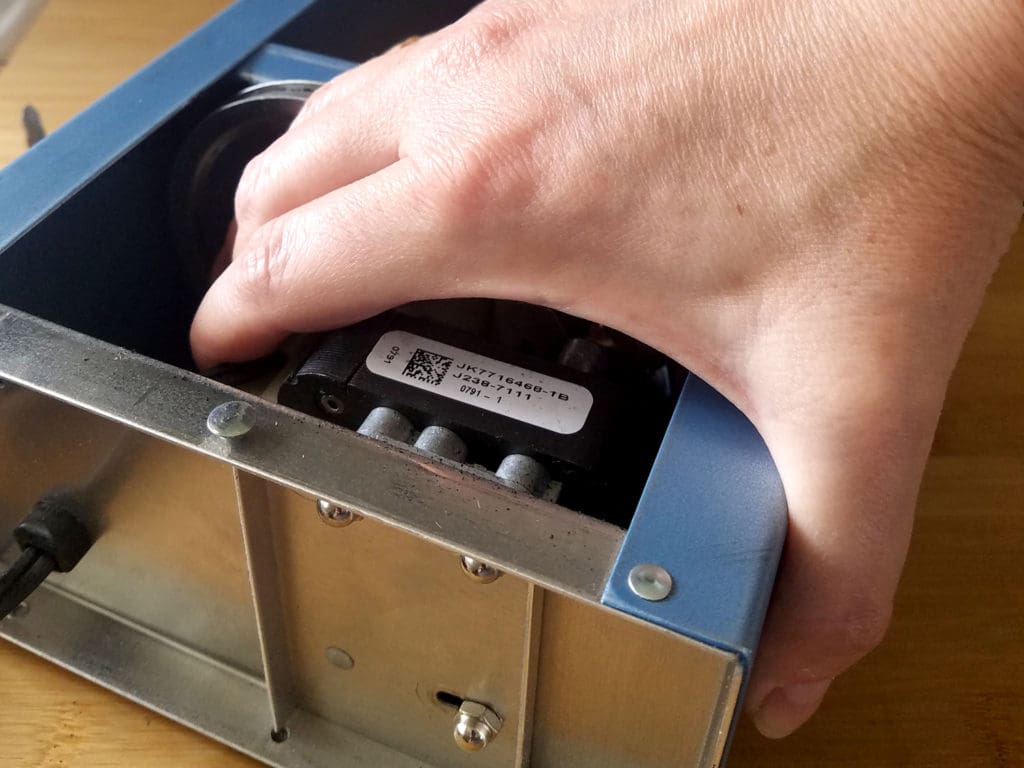 Use your free hand to slide the motor until the mounting screws reach the opposite side of the slotted holes, as shown.