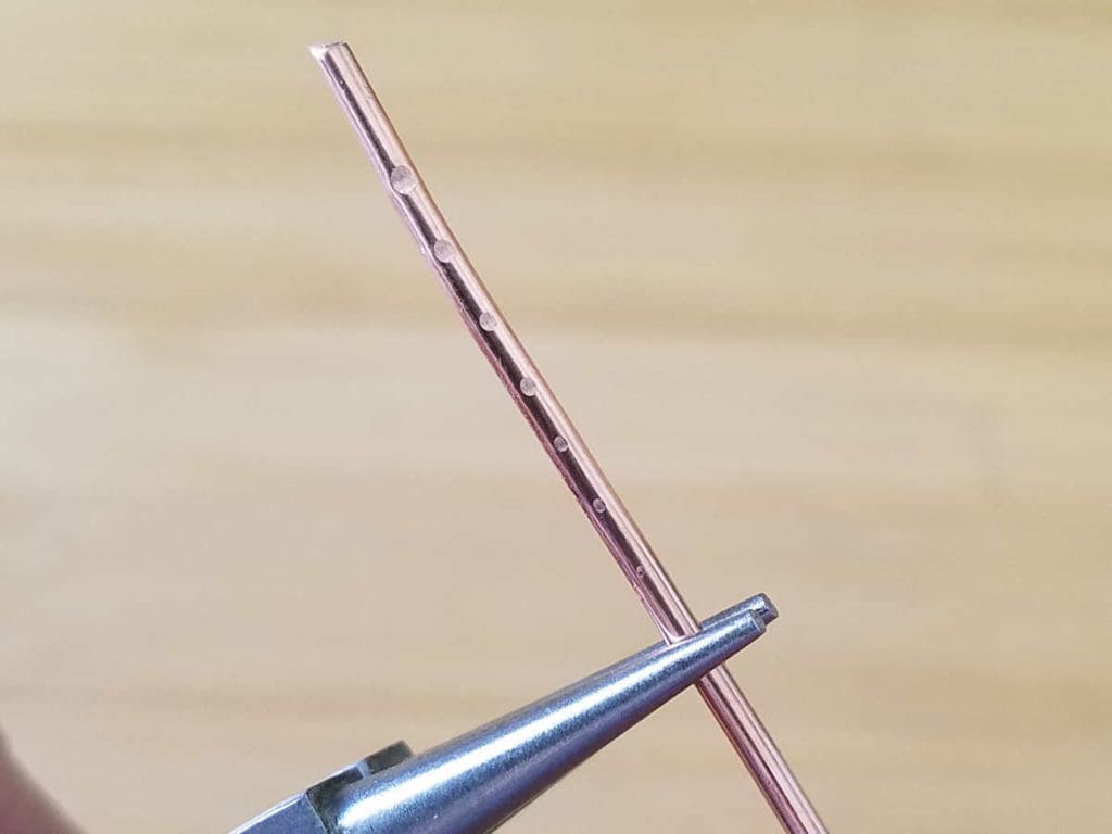 This image shows the tool marks that the author made on a piece of 14ga copper wire using incrementally lighter pressure on her grip. There are seven tool marks fading from the large tool mark created with the first test to a barely visible mark created with the lightest grip. 