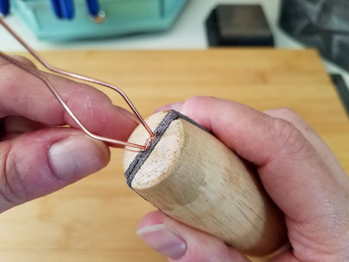 In this image, the author is using a ring clamp to protect the woven portion of the bail while continuing the weaving process.