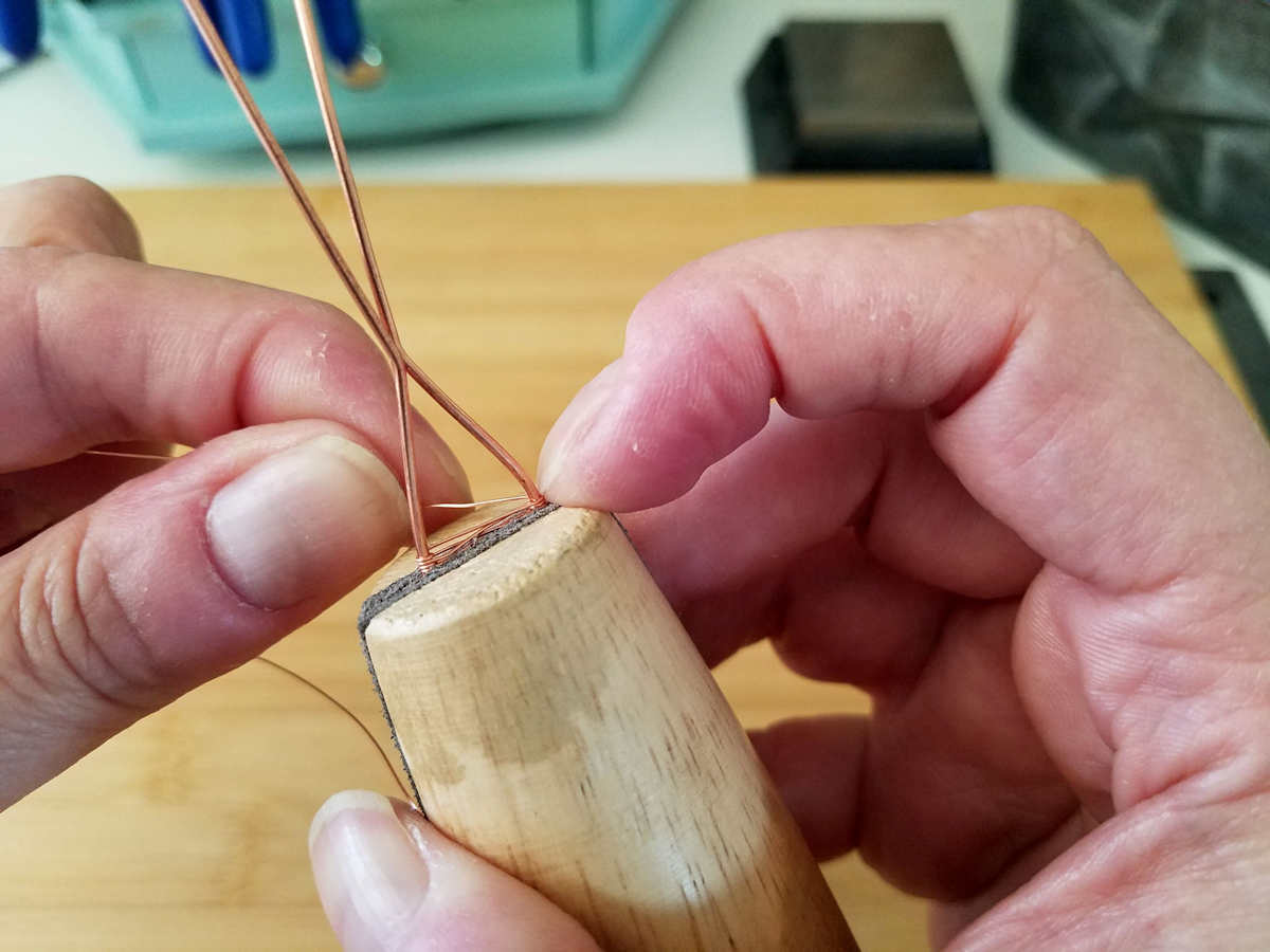 In this image, the author is holding the weave in position with a finger while continuing the weave. 