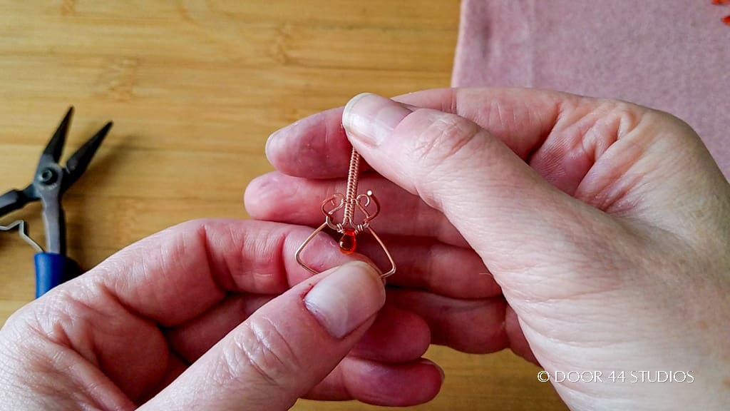 The cut ends of the wires are then fed up through the two loops on the end of the woven components, as shown. 