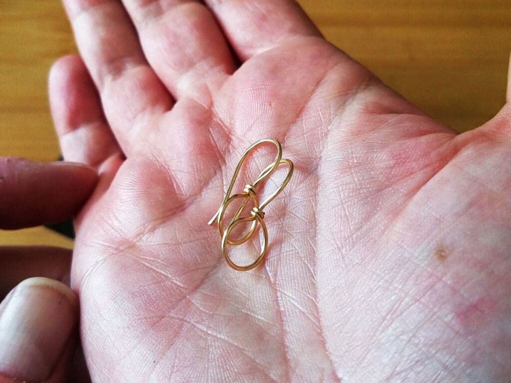 The finished pair of ear wires in the palm of the author's hand