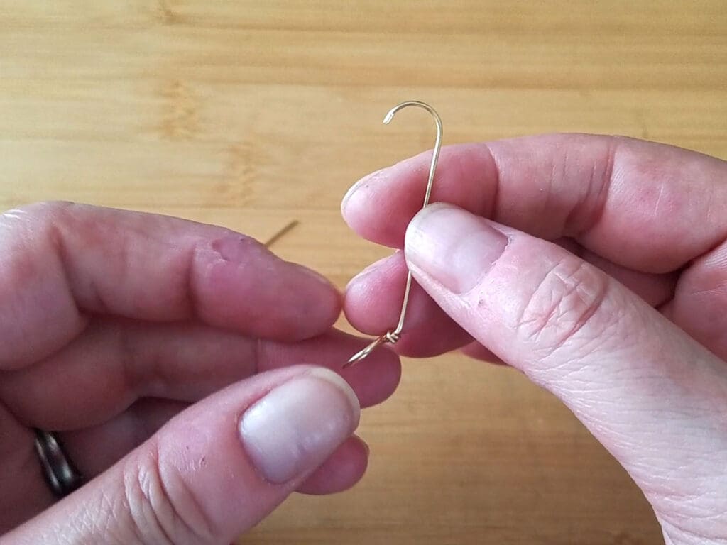 This image shows the shape of the wire up to this point in the process. The loop is angled slightly and the cut end of the wire has been formed into a hook that resembles an umbrella handle 