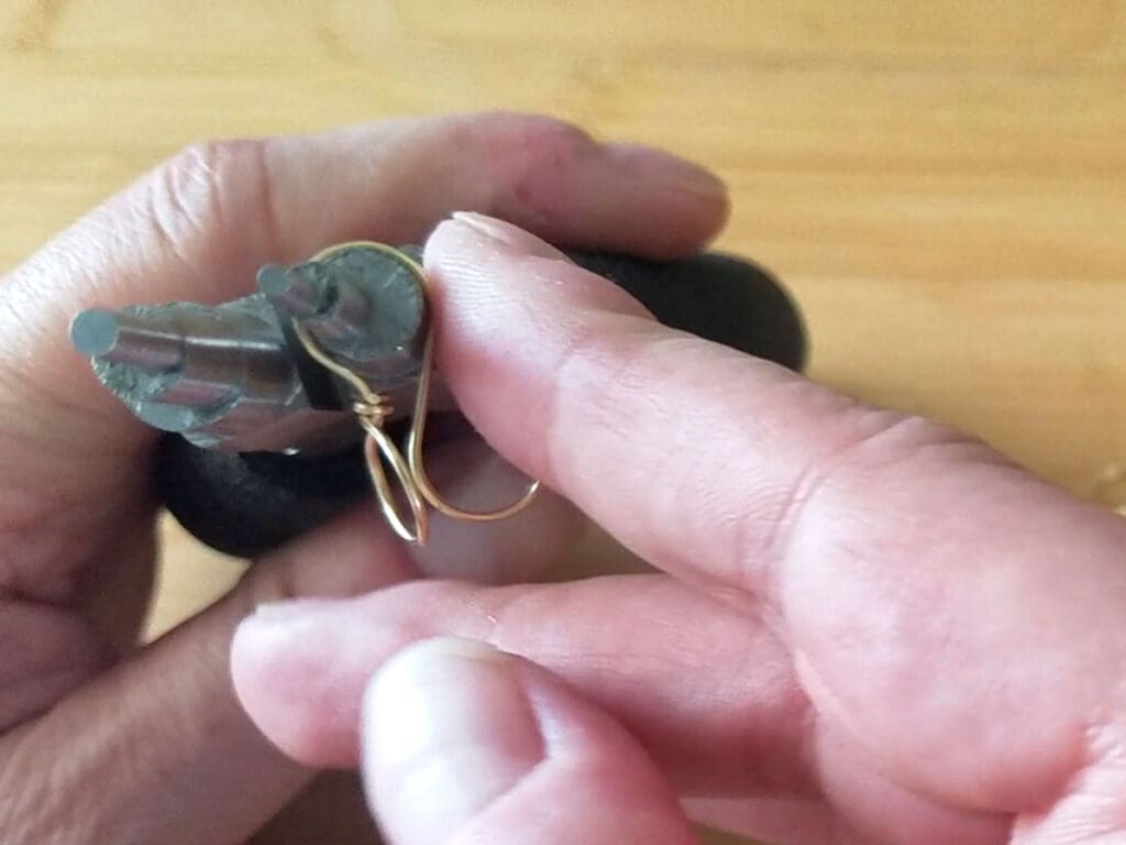 Using stepped bail-making pliers to form the hooked portion of the ear wire that will pass through the pierced ear